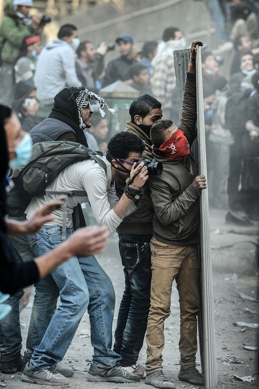 2013年1月25日，在埃及开罗解放广场附近，一名摄影记者在示威者和警察冲突中躲在掩体后拍照。.jpg