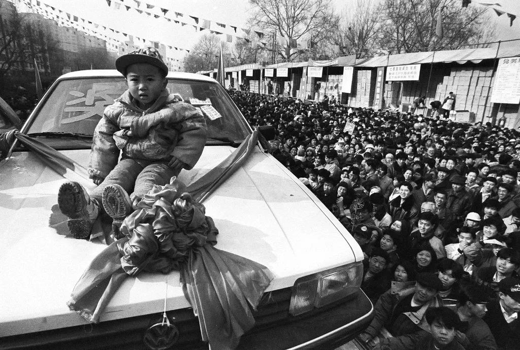 1997年，北京街头的彩票开奖现场，四川来京务工人员伍富贞家3岁的孩子中得一辆轿车。胡金喜摄影像见证四十年.jpg